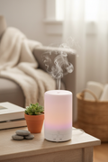 Aldera CalmMist Diffuser on wooden shelf with mist rising, plant and stones nearby